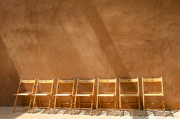istock empty wooden chairs against orange cement wall 535471372