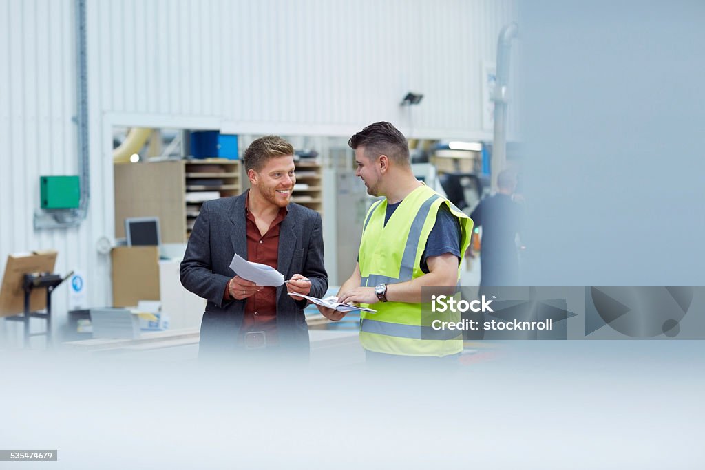 Two colleagues talking to one another at factory Two colleagues talking to one another at factory shopfloor Audit Stock Photo