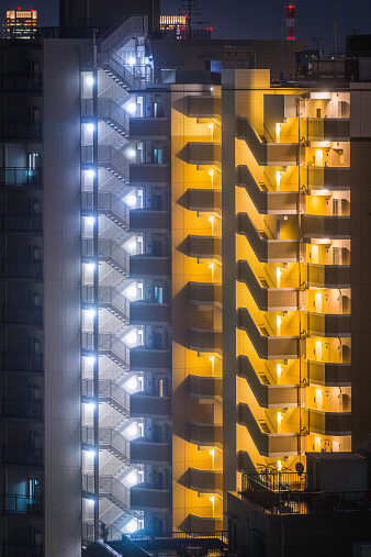 Stairwells and balconies of highrise apartment blocks illuminated at night in the crowded downtown cityscape of Tokyo, Japan. ProPhoto RGB profile for maximum color fidelity and gamut.