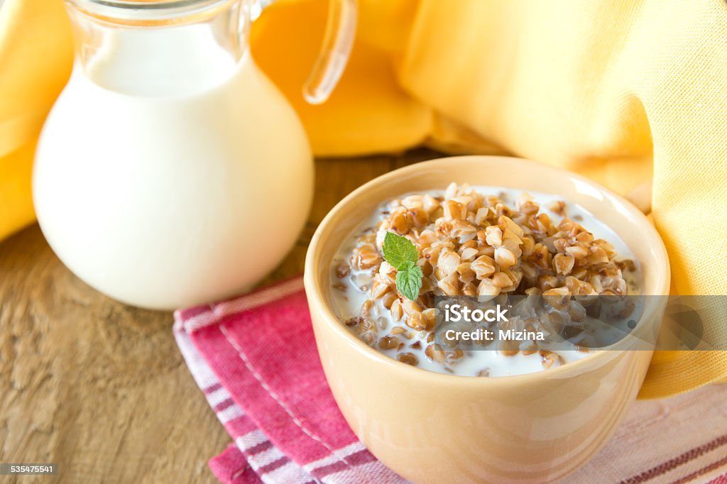 Buckweat with milk Buckweat porridge with milk and mint on wooden table, close up, horizontal. Natural organic vegetarian food (breakfast). Milk Stock Photo