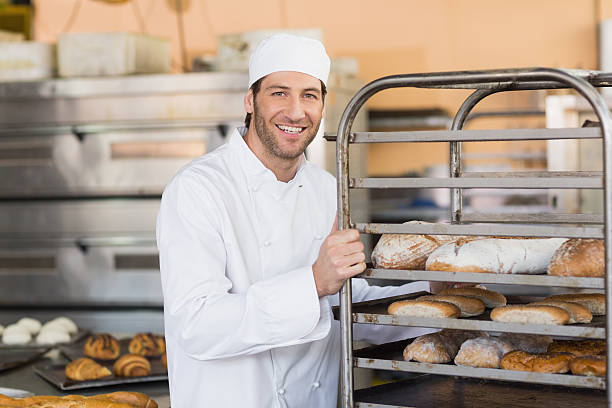 istock Smiling baker pushing tray of bread 535475875