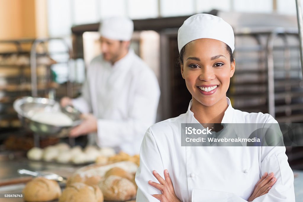 Pretty baker smiling at camera Pretty baker smiling at camera in the kitchen of the bakery Chef Stock Photo