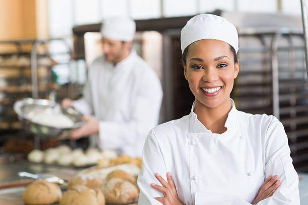 Pretty baker smiling at camera Pretty baker smiling at camera in the kitchen of the bakery restaurant kitchen workers stock pictures, royalty-free photos & images