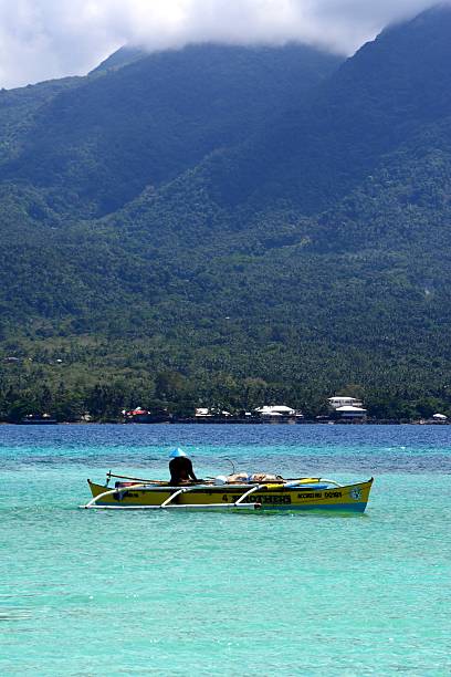 Camiguin, Philippines - February 4, 2014: filipino man on a outrigger canoe in the open sea, off Camiguin island coast.