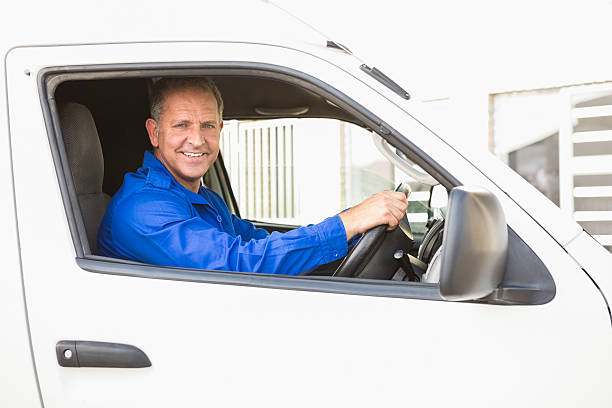 Smiling delivery man driving his van outside the warehouse
