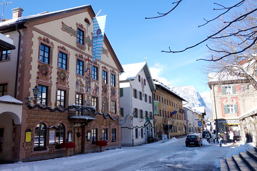 Garmisch-Partenkirchen, Germany - January 31, 2015: Wonderful view over the historical Ludwigstraße in Garmisch-Partenkirchen, Germany. The Ludwigstraße in Partenkirchen is a popular street for tourists because of the historically painted houses. Here you can see a guesthouse on the left with the Bavarian flag and the museum of local history next to it.