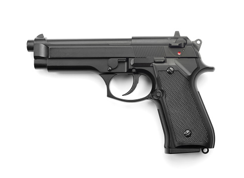 Close-up of two black metal 9mm automatic pistols with bullets all placed on a cement table with a black background.