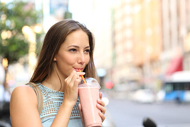 femme manger un milk-shake dans la rue - people eating walking fun photos et images de collection