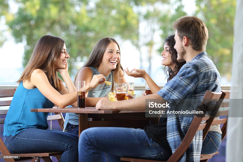 Group of friends talking and drinking at home Group of four friends talking and drinking sitting in a terrace at home Friendship Stock Photo