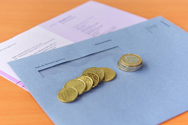 Tax declaration with envelope and Euro coins Paying income, vat, corporate tax in Europe on tax declaration. Photo shows different Euro coins dropped on an envelope of the Dutch Tax department. european union coin photos stock pictures, royalty-free photos & images