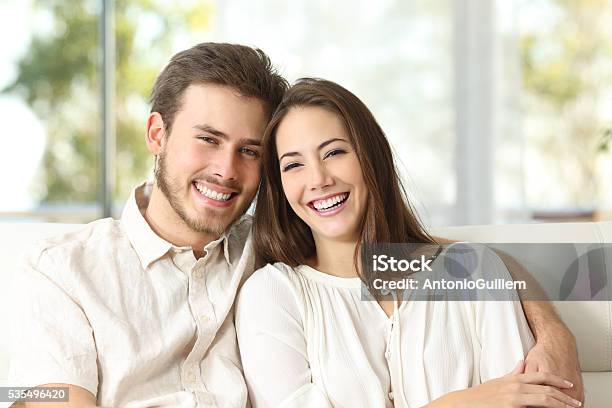 Paar Zu Hause In Die Kamera Schauend Stockfoto und mehr Bilder von Paar - Partnerschaft - Paar - Partnerschaft, Lächeln, Zahnpflege