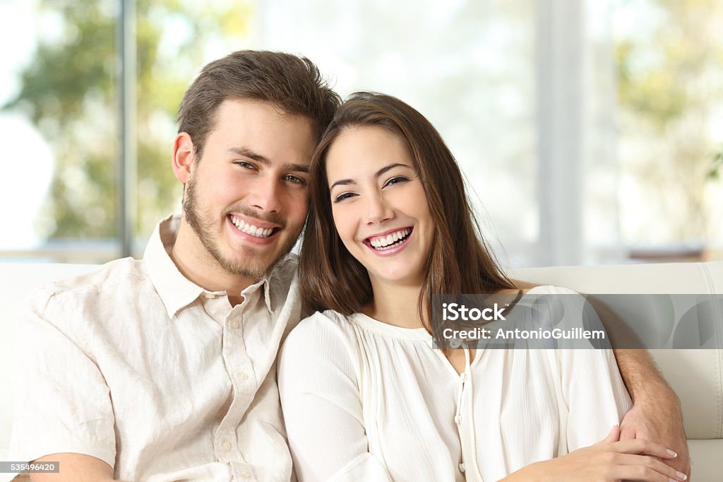 Couple at home looking at camera Happy couple sitting on a couch at home and looking at camera Couple - Relationship Stock Photo