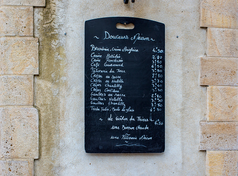Saint-Jean de Luz, France - May 21, 2016: Creperie menu blackboard on a stone wall in a street of Saint-Jean de Luz.
