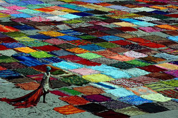 Agra, İndia - September 23, 2006: A man is collecting the colorful saris laid to dry on the beach