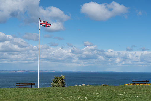 View along the English Channel with a flying Union Jack flag. Image taken in Devon, UK