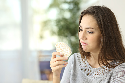 Girl disgusted looking a dietetic cookie. Bad diet concept