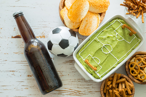 Selection of party food for watching football game, soccer field dip, top view