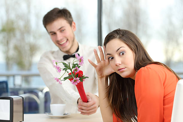 Woman rejecting a geek boy in a blind date Disgusted woman rejecting a geek boy offering flowers in a blind date in a coffee shop interior gift for girlfriend stock pictures, royalty-free photos & images