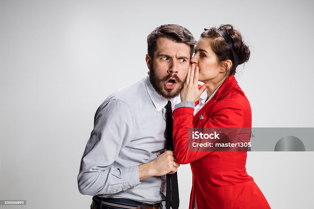 Young man telling gossips to his woman colleague at the Young man telling gossips to his woman colleague at the office. Intrigues and wasting time concept Gossip Stock Photo