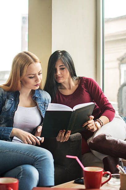 istock Two female friends reading book at a cafe. 535510782