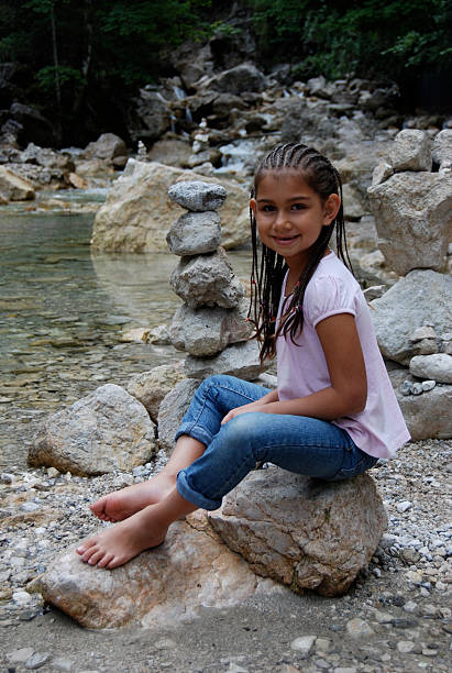 Happy girl with braids sitting by a river