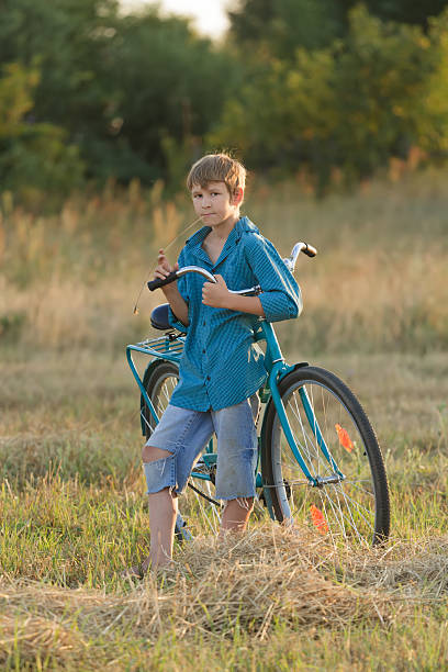 istock Young boy holding bicycle in farm field 535513287