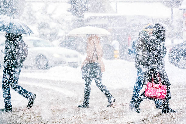 fußgänger überqueren sie die straße auf einem verschneiten tag - snow walking stock-fotos und bilder