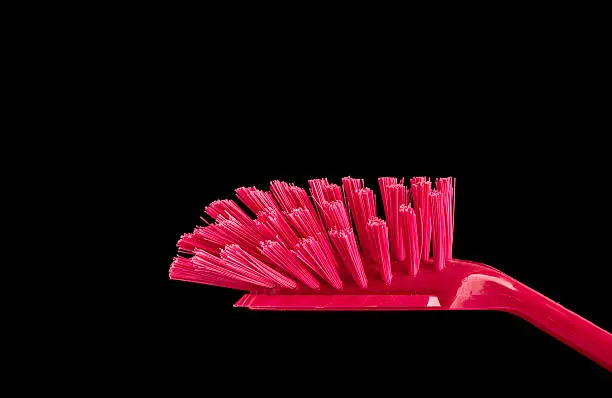 Dish brush in close-up. Red plastic dishwashing equipment.