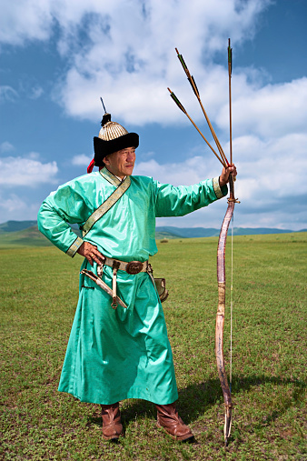 Mongolian archer at Naadam festival, standing on the grass, The blue sky on the background