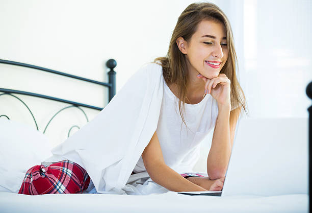 istock Cheerful student girl studing with laptop in bed 535516442