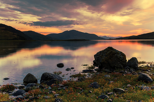 Scottish loch on Skye island at sunset with mountains in the background.