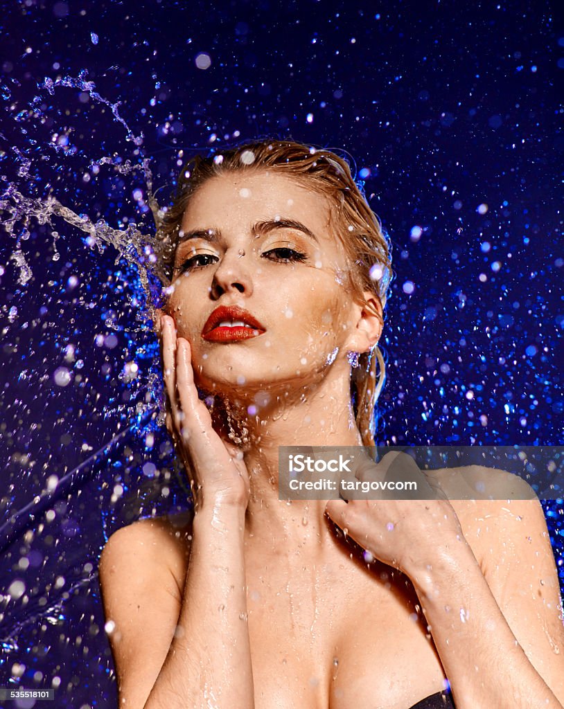 Wet woman face with water drop Wet woman face with water drop. Droplets fly on dark background Make-Up Stock Photo