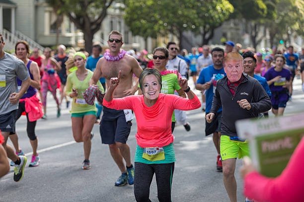 San Francisco Bay to Breakers 2016 Event San Francisco, CA, USA - May 15, 2016: This 12K race is one of the largest and oldest running events in the world. It attracts more than 50,000 runners and 100,000 spectators every year. This race includes both serious runners and those out for a fun Sunday run. Many wear fun and funky costumes to show their spirt. You will also find a few people in just their birthday suit. Two runner wearing Hillary Clinton's and Trump's masks. hillary clinton stock pictures, royalty-free photos & images