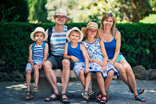 family of five sitting outdoors on a hot summer day for a family portrait