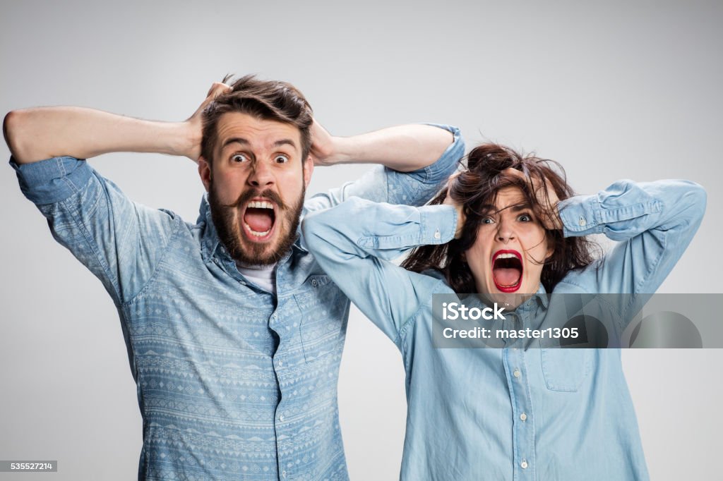 Close up photo of angry man and woman touching their Close up photo of angry man and woman touching their heads and screaming Couple - Relationship Stock Photo