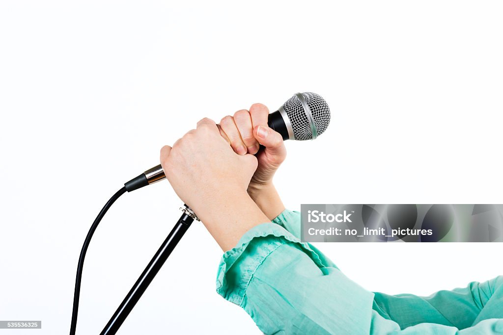 female hand with microphone woman holding with two hands a microphone with stand in front of a white background 2015 Stock Photo