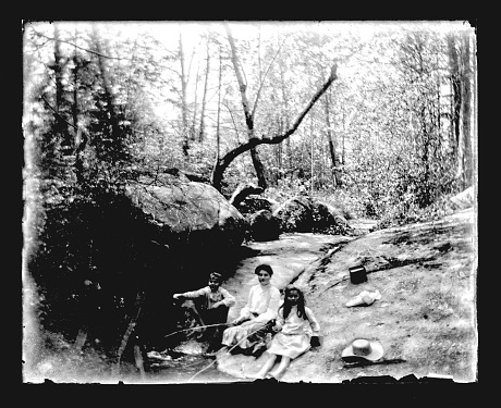 Beautiful Black and White portrait of a family on a Summer outing in the woods fishing in a stream wearing Victorian-era clothing. The image was digitally restored from a glass plate taken circa 1890.
