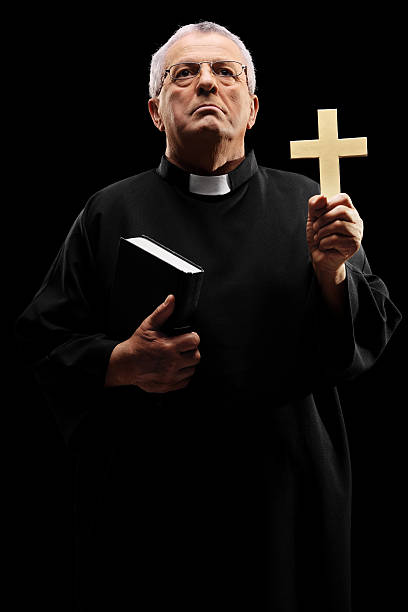 istock Mature priest holding a cross and looking up 535541467