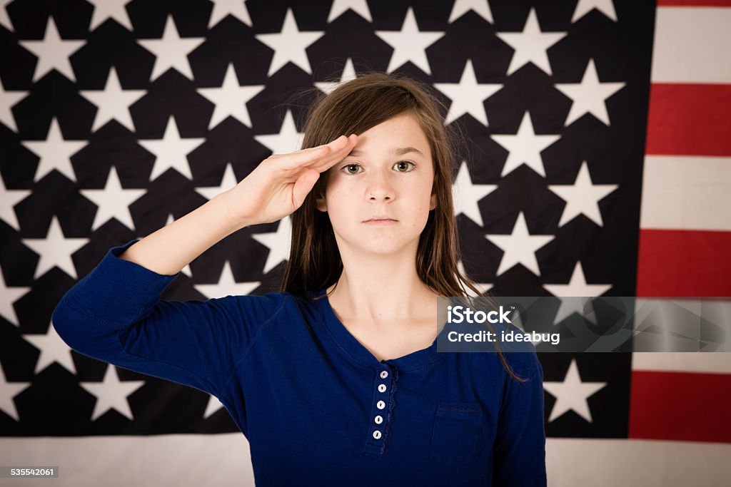 Young Preteen Girl Saluting in Front of American Flag Color photo of a serious, young preteen girl saluting America and our troops in front of a large American flag. 10-11 Years Stock Photo