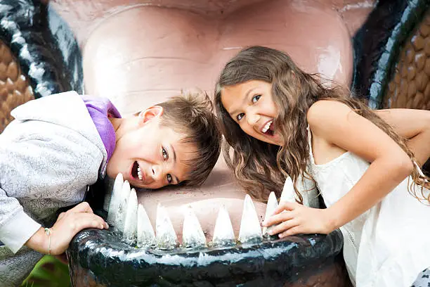 Two happy children are having fun pretending to be in the dinosaur jaw