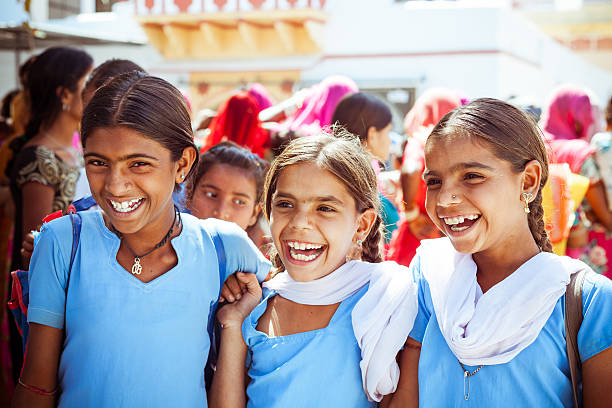 Sabbalpura, India - March 15, 2014: Group of happy indian school girls wearing blue school uniforms posing in the rural village, Rajasthan, India.