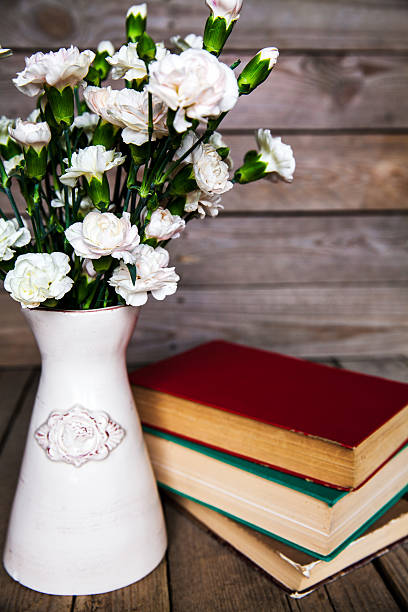 istock gentle carnation in the old book on a wooden background 535570863