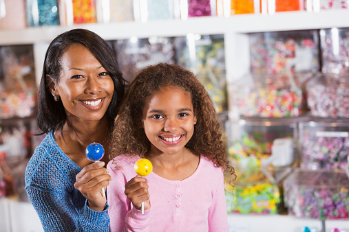 African American mother (30s) and daughter (9 years) in candy store.