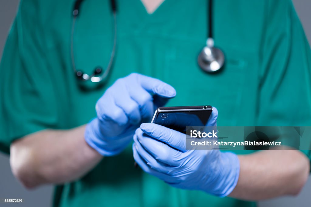 Surgeon using mobile phone Horizontal view of surgeon using mobile phone 2015 Stock Photo