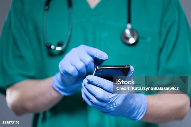 Surgeon Using Mobile Phone Stock Photo - Download Image Now - 2015, Adult, Adults Only