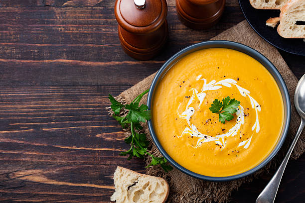Pumpkin and carrot soup with cream and parsley Top view Pumpkin and carrot soup with cream and parsley on dark wooden background Top view Copy space soup photos stock pictures, royalty-free photos & images