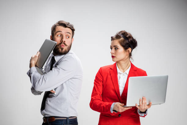 istock The young businessman and businesswoman with laptops communicating on gray 535588708