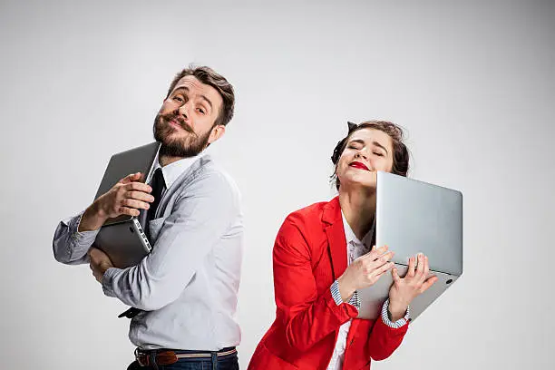 Photo of The young businessman and businesswoman with laptops on gray background