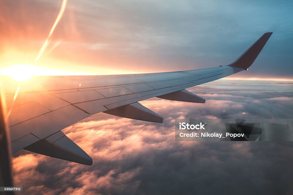 Above the clouds. View from the window of an airplane at sunset. Aircraft Wing. Airplane Stock Photo