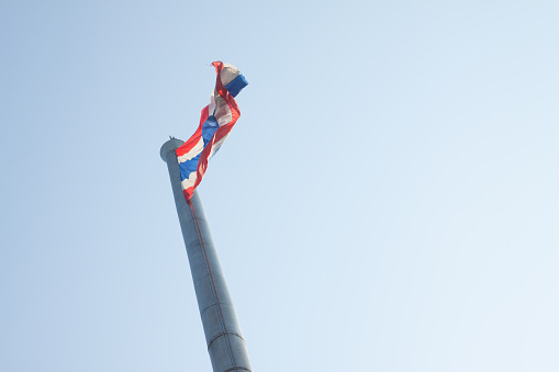 Flag of Thailand on huge flagstaff with clear sky.